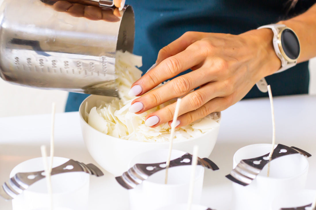 Hands pouring soy wax flakes into bowl