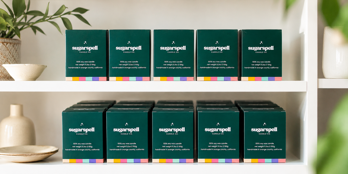 Rows of Sugarspell candle boxes on white retail shelves in a bright shop